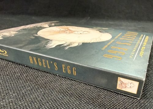 Vista en perspectiva de la funda de Angel’s Egg, con la ilustración de Yoshitaka Amano y el título dorado.