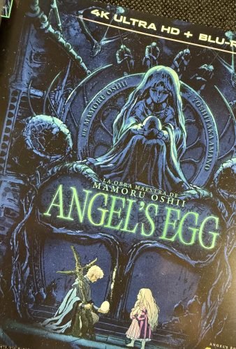 Primer plano del libreto de Angel’s Egg, donde destacan la figura de la niña, los motivos circulares y el título en tonos verdes.